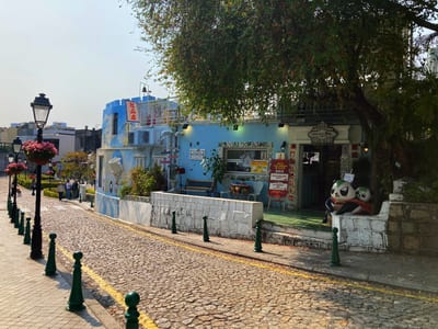 A blue gift shop on a cobbled street, green bollards along the kerb