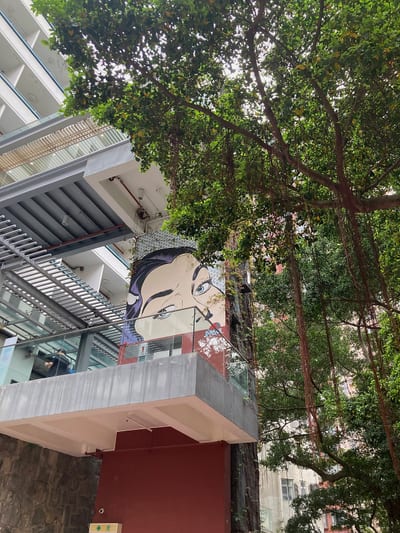 A painted face on a wall, half hidden by trees