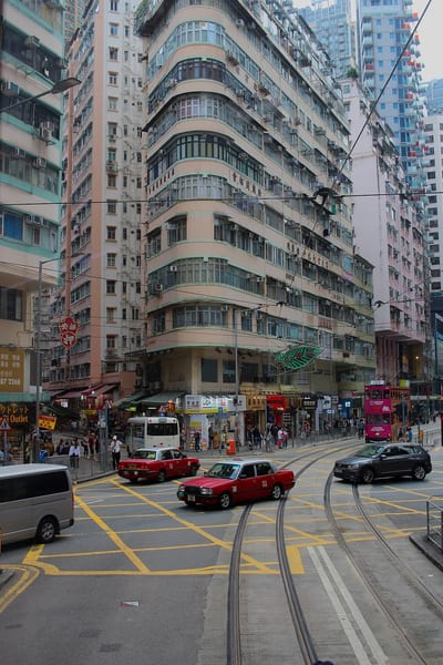 A curved corner building and red taxis at a Hong Kong junction