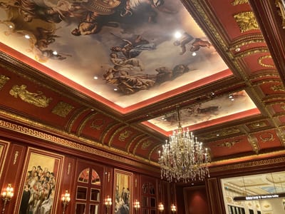 A painted ceiling and chandelier in a red and gold room