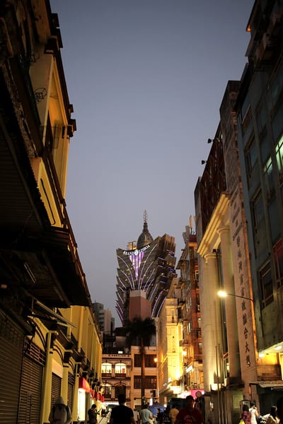 A Macau street at dusk, the Grand Lisboa lit at the far end