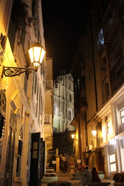 A lantern-lit lane in Macau, the Ruins of St. Paul's glowing at the top of the steps