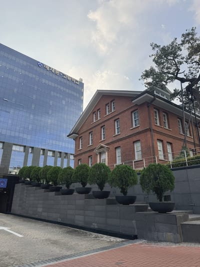 The blue glass tower and the red brick hall beside it
