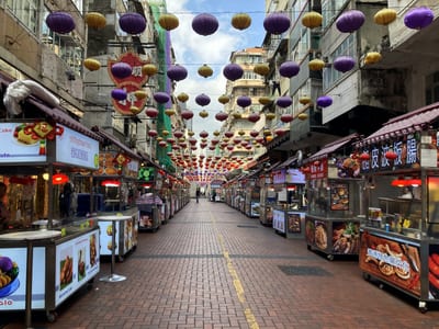 Food stalls down a narrow street, lanterns strung overhead the whole way