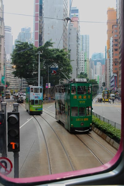Two green trams passing on a Hong Kong street, seen from inside one